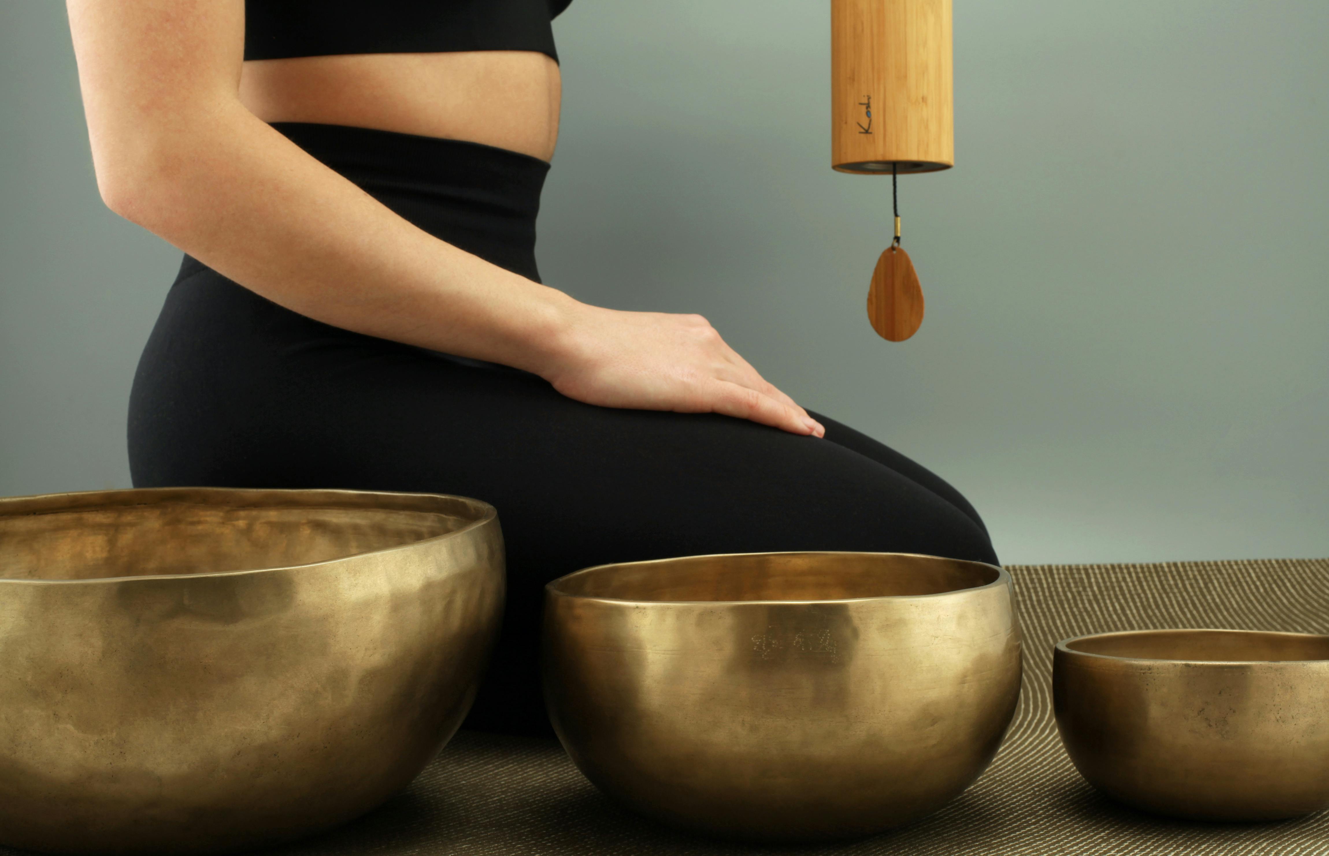 Person meditating with singing bowls